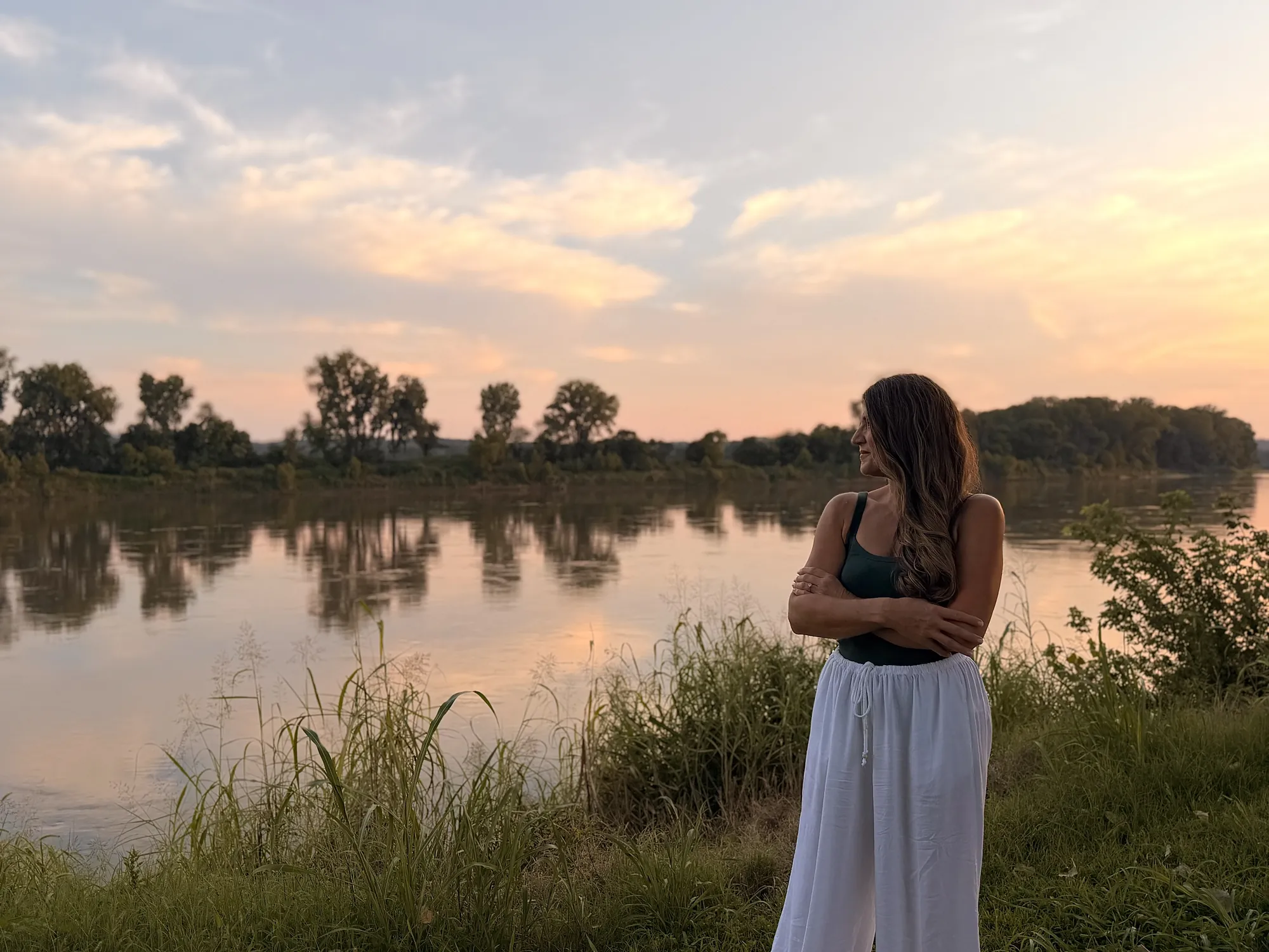 Teresa Nerem, licensed massage therapist, standing by the river at sunset